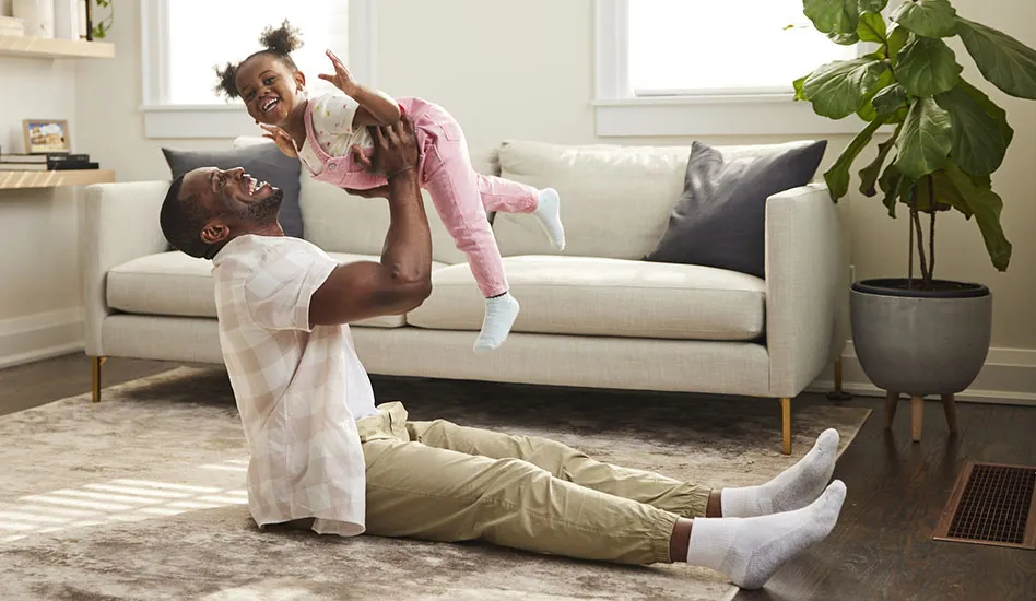 father playing with his daughter on the living room floor